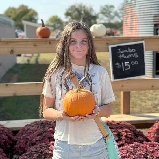 Student holding up a pumpkin outdoors