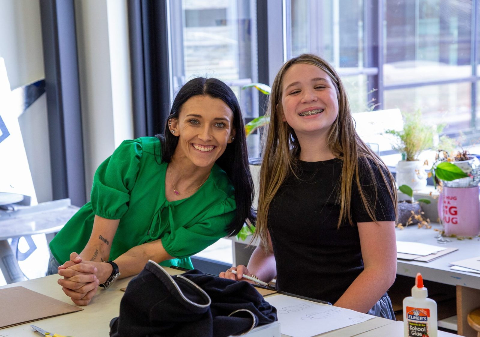 Educator posing with student at student's desk